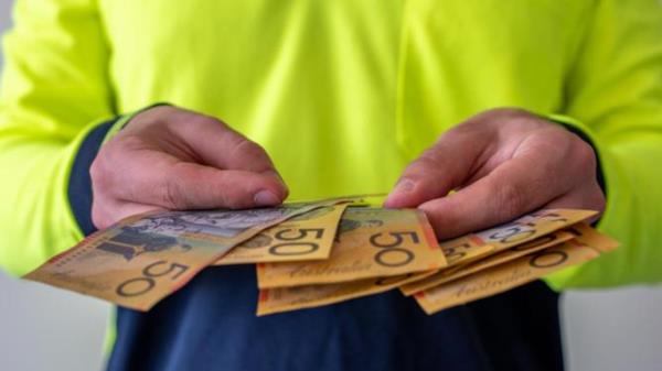 View of a tradesman in high visibility clothes holding australian dollar notes